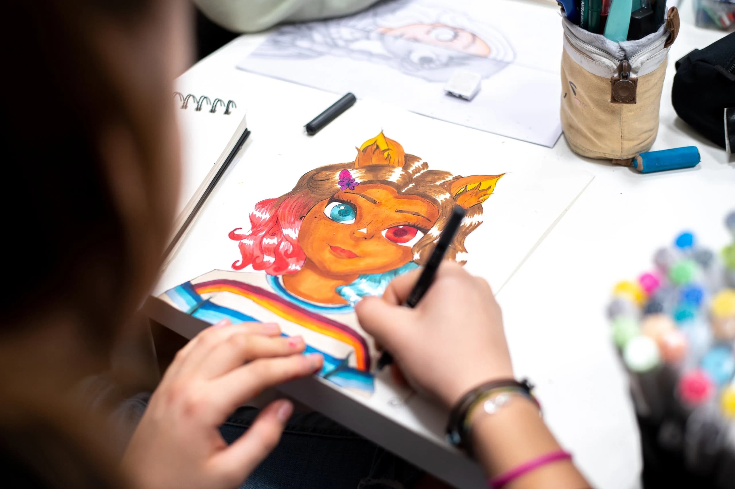 Una ragazza colora con i pennarelli un'illustrazione in stile manga