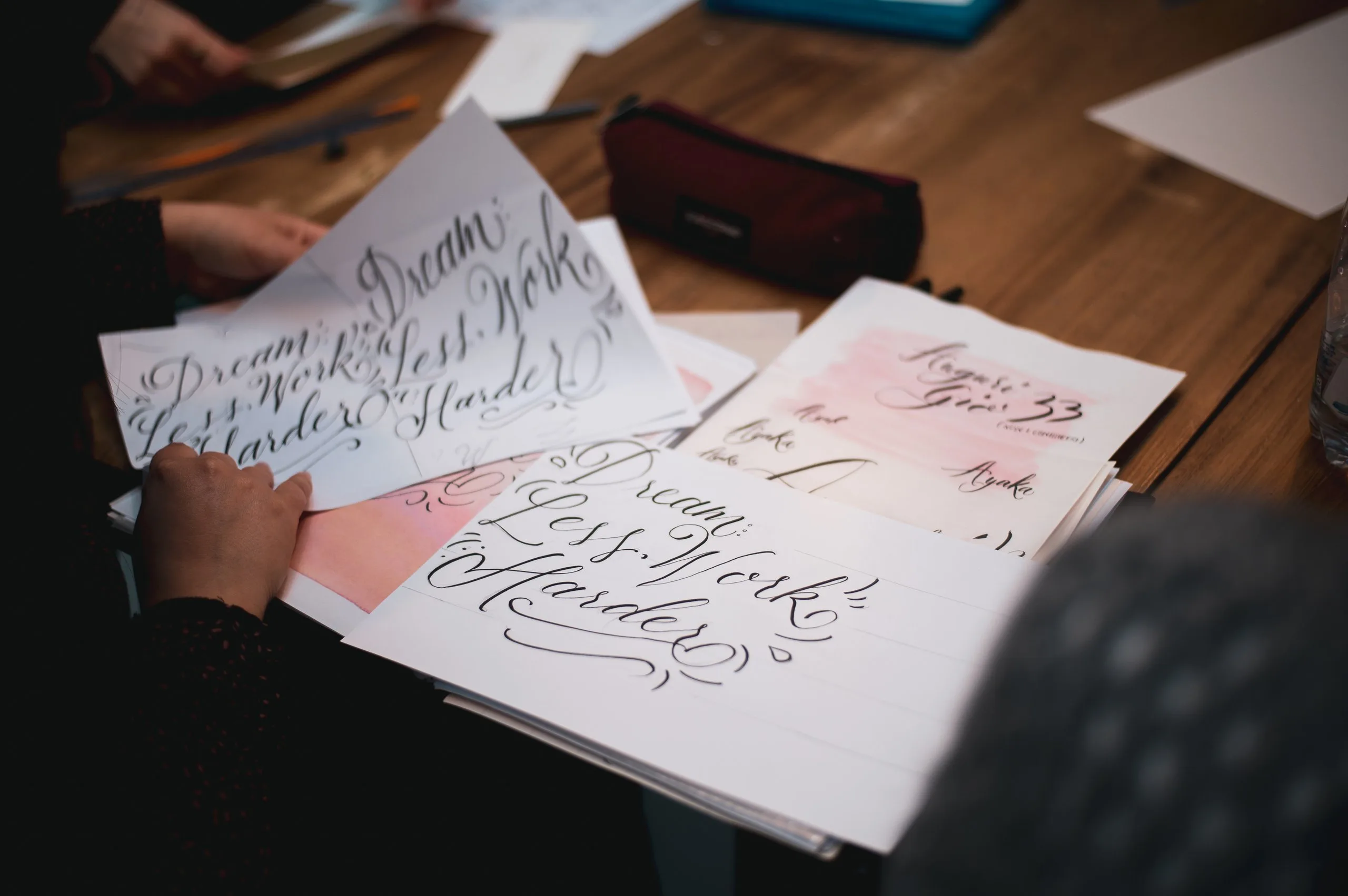 Fogli di lettering con scritte in corsivo calligrafico sul tavolo
