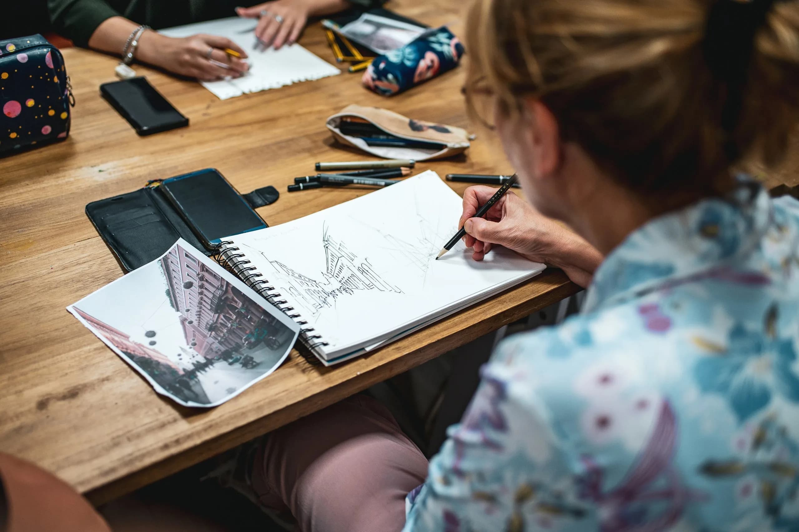 Un'allieva disegna uno scorcio di citta' a china su un album, durante un corso di Urban Sketching