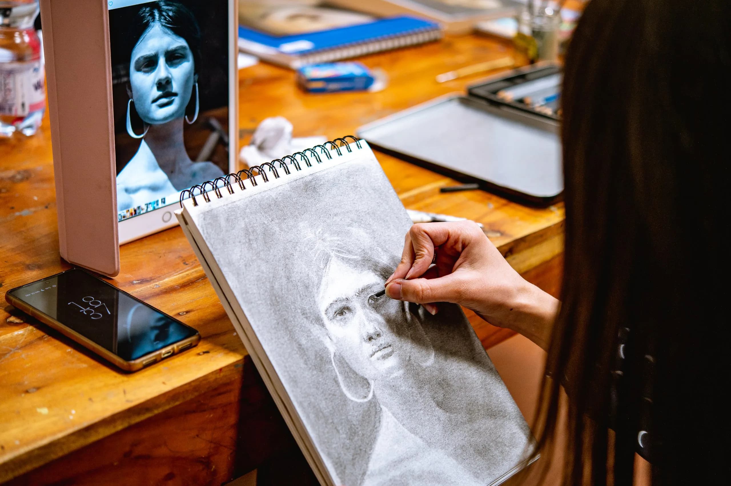 Un'allieva disegna a matita un ritratto femminile copiandolo da uno schermo
