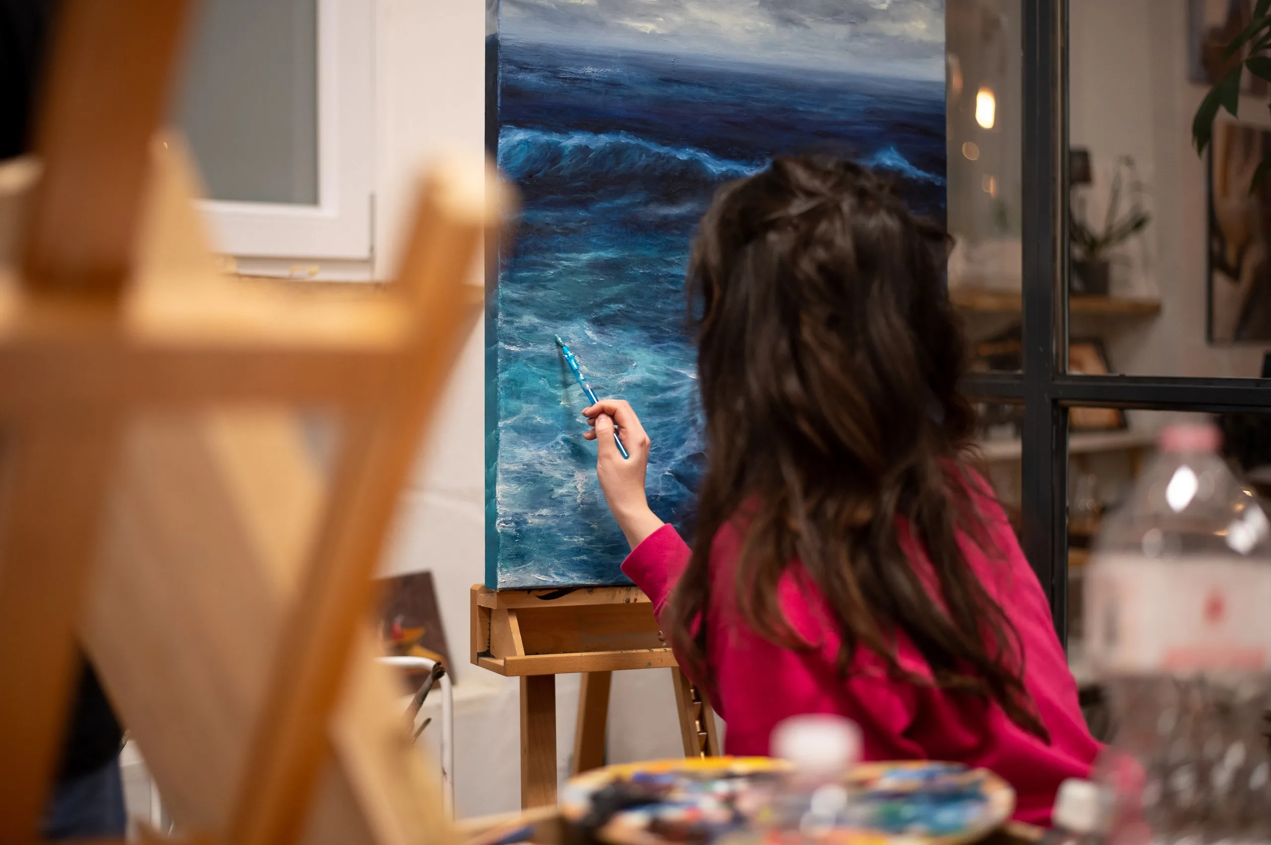 Una ragazza dipinge un mare in tempesta su una grande tela