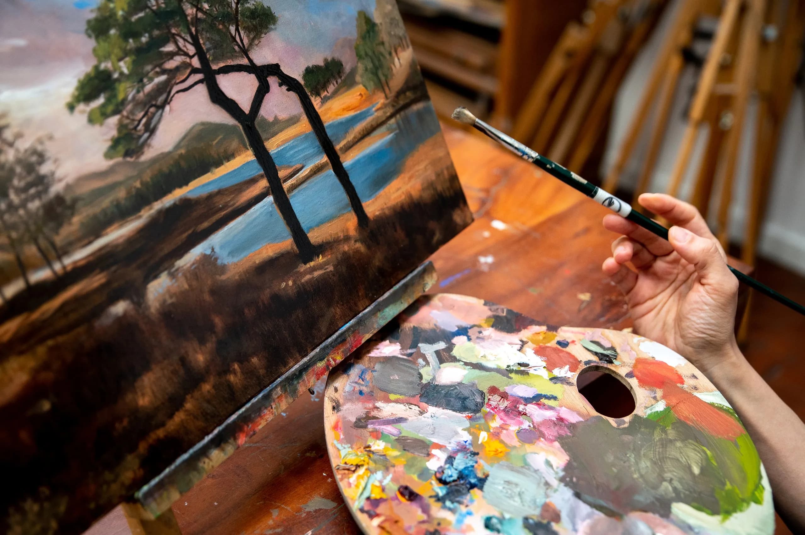 Un paesaggio con due pini dipinto a olio e una tavolozza piena di colori