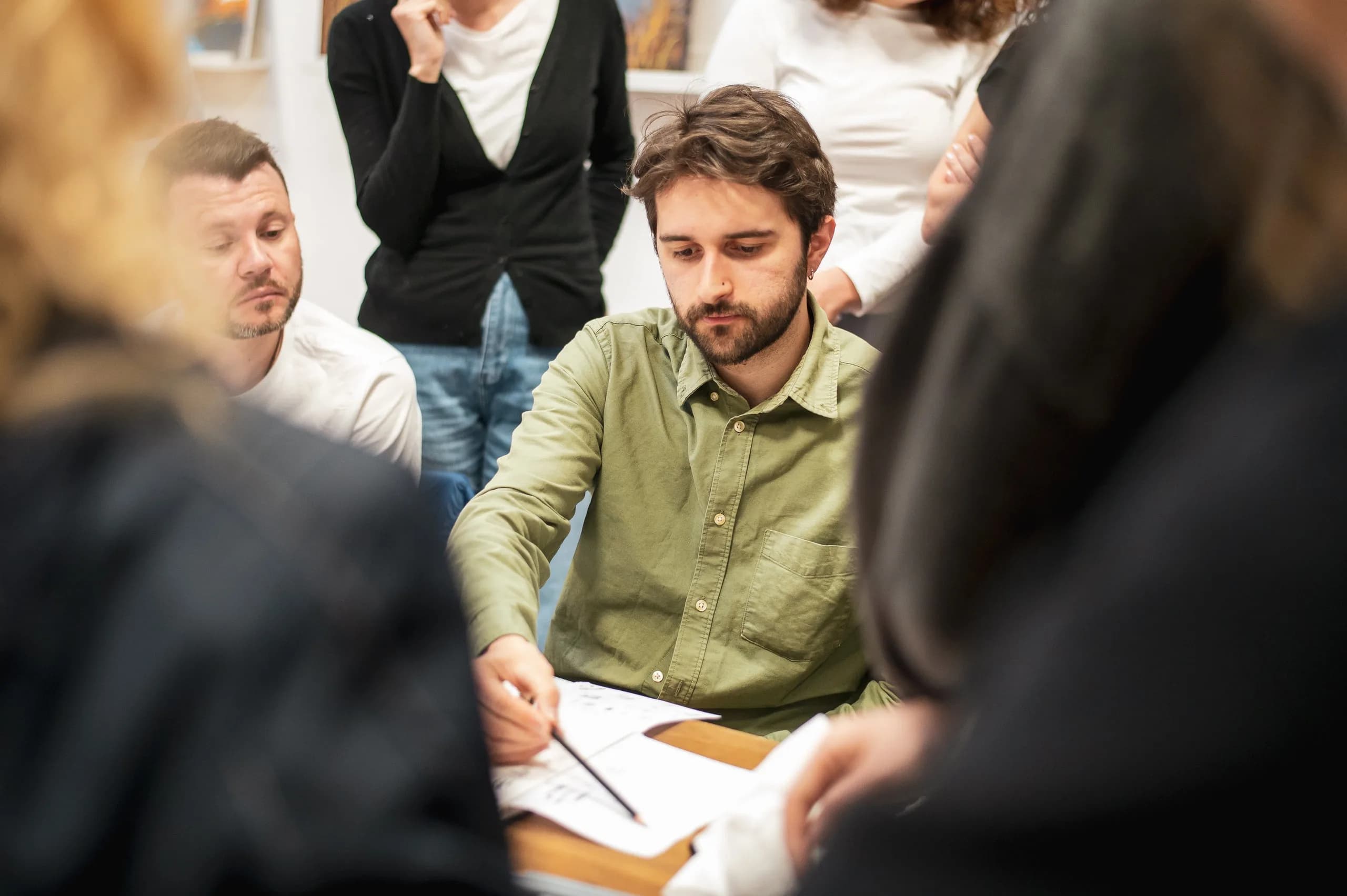 Simone Mostacci disegna al tavolo circondato dagli allievi